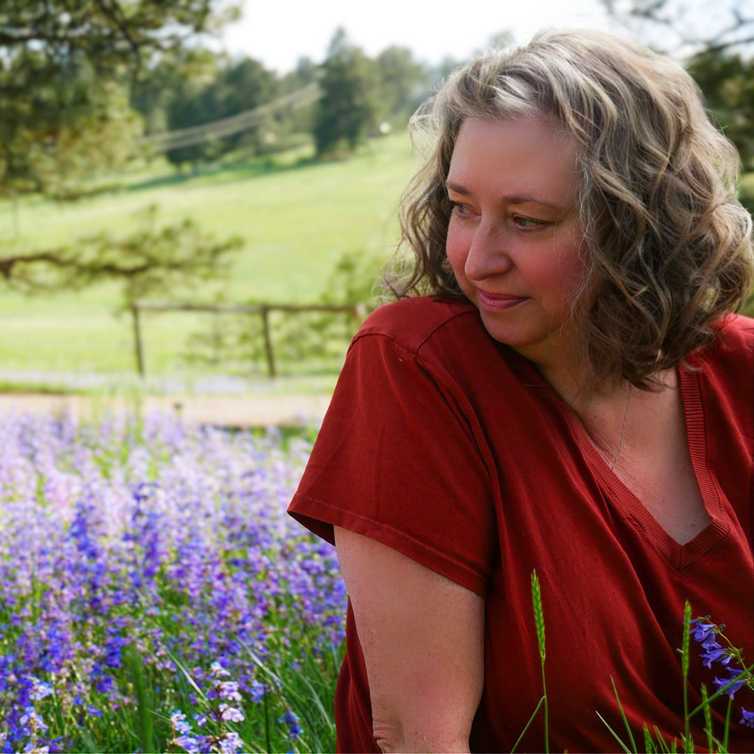 Casey in red shirt in front of flowers