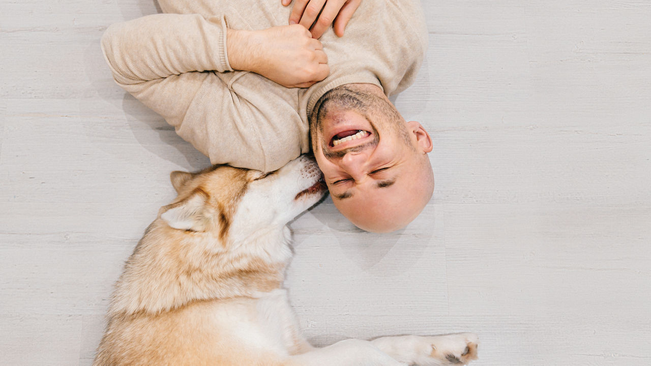 Man laying on floor with husky laying next to him.