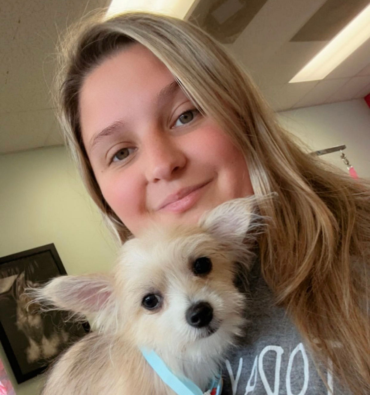 A blonde woman holding a small dog